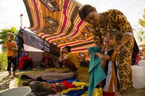 A Yazidi Kurdish mother washes off her sick toddler in a refugee camp in a northern Iraqi city.  (Photo by Joseph Rose/BGR)