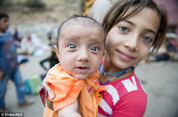 Yazidi girl holds brother, waits for bread in Dohuk refugee camp
