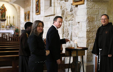 British Prime Minister David Cameron (C) lights a candle as he visits the Church of the Nativity in 2014. (REUTERS/Thomas Coex/Pool)